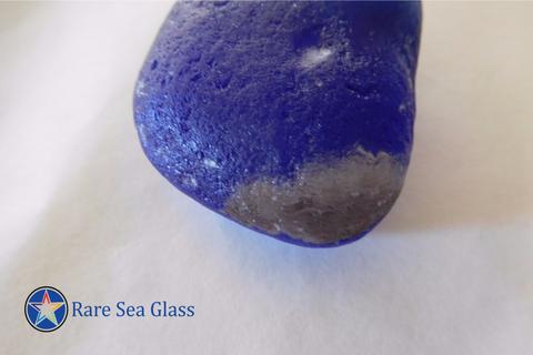 World globe sea glass piece found at Davenport Beach showing brown landmass pattern against blue glass